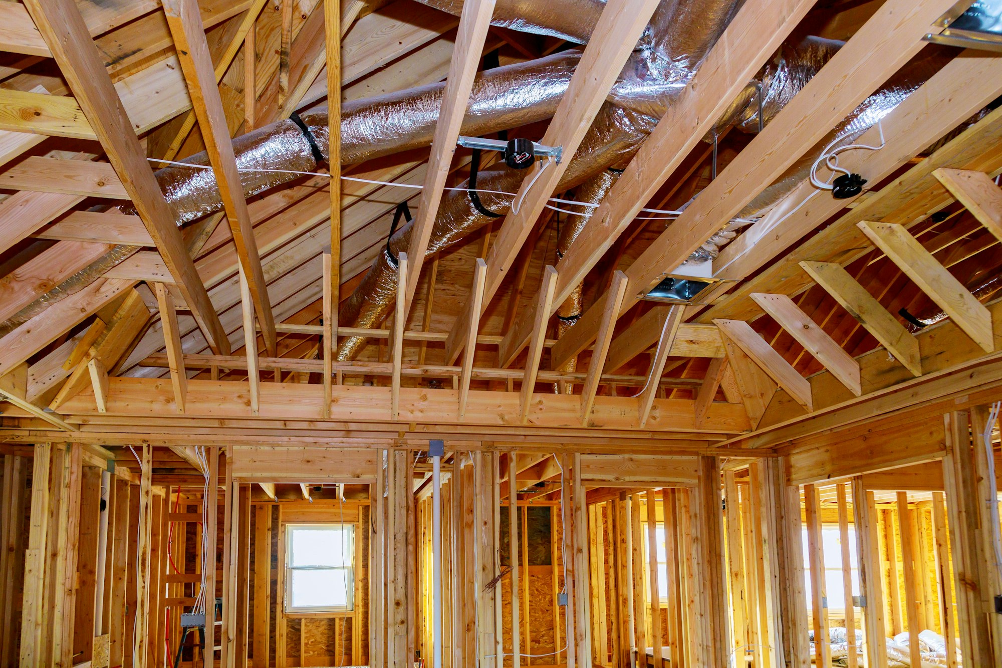 Installation under construction with wooden beams of HVAC tubing vents heating system on the roof,