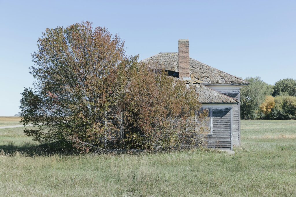 One room school house building by a road on the prairie.